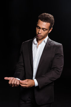 mixed race man standing and touching suit isolated on black