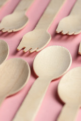 eco-friendly and disposable kitchenware pattern. wooden spoons and forks at pink coral background.