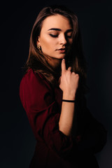 beautiful girl with evening makeup looks down. dark background.