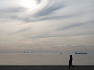 A guy in a hoodie walking near the docks - cloudy weather