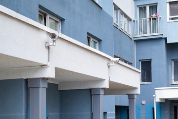 Fototapeta na wymiar outdoor surveillance camera on a blue white wall of an apartment building in a residential area of the city during the day