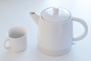 white ceramic teapot and cup on a white table