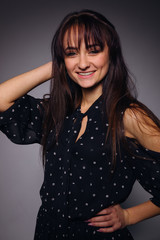 young woman in a polka dots dress look at camera and smile. gray