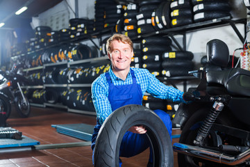 mechanic holding new tyre for motorcycle