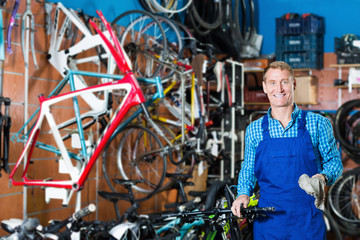 Male seller in uniform picking new bicycle wheel hands