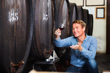 Obraz na płótnie Canvas Man wine maker holding wineglass for tasting