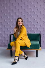 stylish businesswoman in a yellow suit sitting on armchair and l