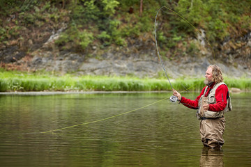 Flyfishing in waterproof clothing in river.