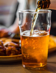 pouring beer in glass from bottle on bar or pub