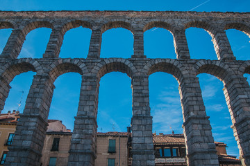 Ancient Roman aqueduct on Plaza del Azoguejo square and old building towns in Segovia, Spain.