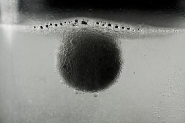 White medication tablet dissolving in a glass filled with water. Act on a black background.