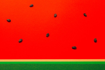 Summertime minimal concept. Watermelon seeds on red and green paper