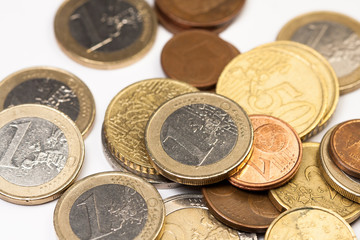 Different amounts of scattered European coins on a white background.