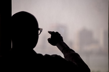 silhouette of man pointing out the window