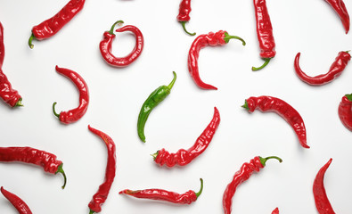 many red whole fruits of hot pepper and one green on a white background