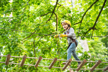 Rope park - climbing center. Child boy having fun at adventure park. Go Ape Adventure. Child boy...