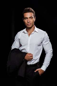 handsome mixed race man standing with hand in pocket isolated on black