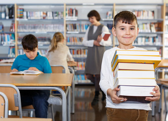 Smiling boy standing with pile of books
