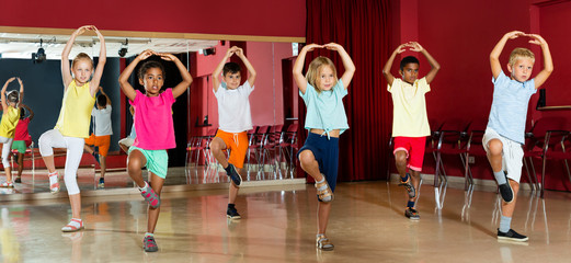 Childrens trying balance movements of ballet in classroom