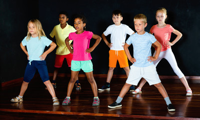 Group of smiling  little boys and beautiful girls having dancing class  in studio  in the evening