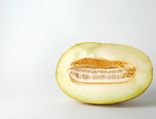 half of ripe yellow melon with seeds isolated on white background
