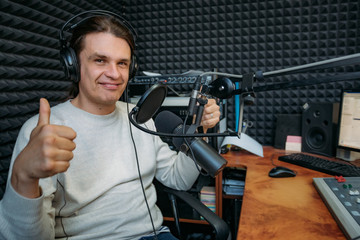 Smiling talking radio DJ shows thumbs up in radio studio
