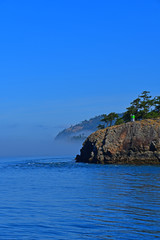 Morning fog hugs the coast of Deception Pass as it enters the Salish Sea in Washington State