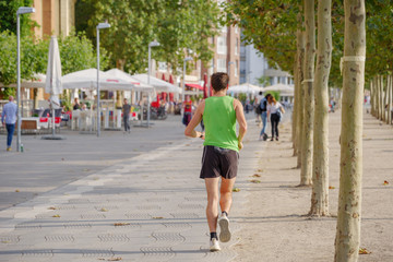 Fototapeta na wymiar Man or runner jog and run at Rheinufer Promenade on the sidewalk or walking street on riverside of Rhein River in Düsseldorf, Germany. 