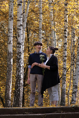 A middle-aged woman walks through the autumn forest with a teenager. Mother and son are standing on the stone steps. Family resting together on the weekend.