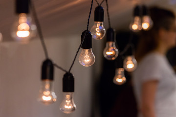 Close up view of vintage decorative light lamp bulb glowing on the ceiling indoors. Transparent lamps glowing with warm light