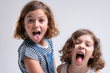 Playful little girls sticking out their tongues