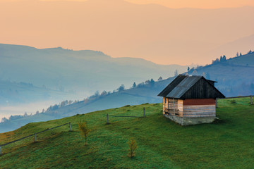 Fototapeta na wymiar amazing beautiful rural area at dawn. morning in the carpathian mountains. fog in the distant valley. woodshed on the hill