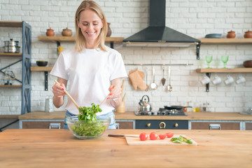 beautiful young smiling woman making salad in the kitchen. Healthy food. vegetable salad. Diet....