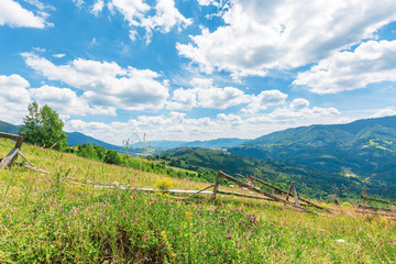 wonderful landscape of rural area at noon.  amazing cloudscape above the distant mountain ridge. beautiful sunny weather. wooden fence on the grassy meadow