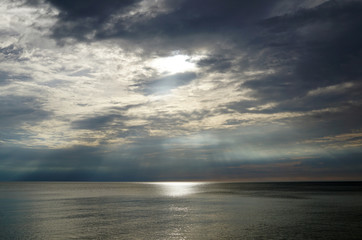 Dark sunset. The sun's rays shine over the surface of the lake