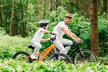 Obraz premium happy father and son smiling while riding bicycles