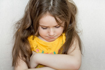 a portrait of emotional upset pensive and meditative little girl on a white background