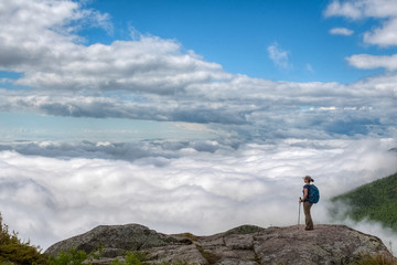 Lone active woman at the edge of the cliff, above the clouds, Quebec, Canada