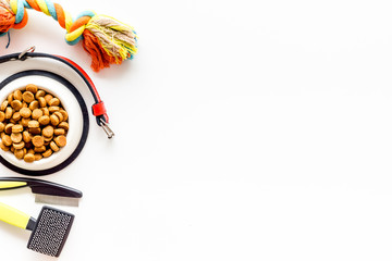 Dry dog food in bowl and toys on white background top view space for text