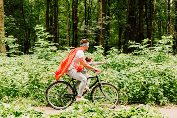 side view of father and kid riding bicycle while boy looking forward