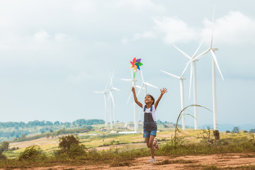 Cute asian child girl is running and playing with wind turbine toy  with fun in the wind turbine...