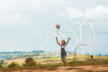 Cute asian child girl is running and playing with wind turbine toy  with fun in the wind turbine field © pingpao