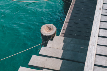 Fototapeta premium Old wooden pier near the blue sea with nautical ropes and text space,View of a rocky coast in the morning at National Park, Rayon g province, Thailand