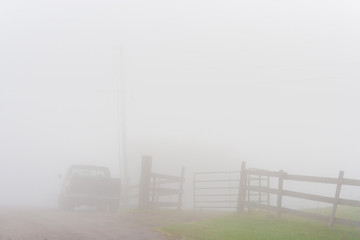 Pickup truck and a stockade gate and fence in early moring fog, Stowe, Vermont, USA