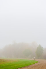 Solitary man walking along a dirt road on a foggy morning, Stowe, Vermont, USA