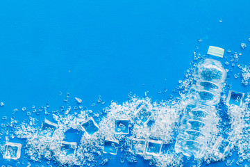 ice cubes and bottle of water on blue table top view mock up