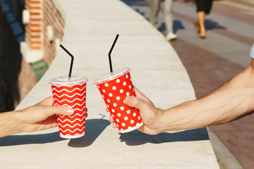 Two friends or couple holding coffee cups together. Agreement, meeting or celebration. Man and woman bonding. Cheers!