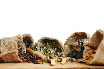 Herbal group in sack bag With a wooden spoon placed in front of a white background