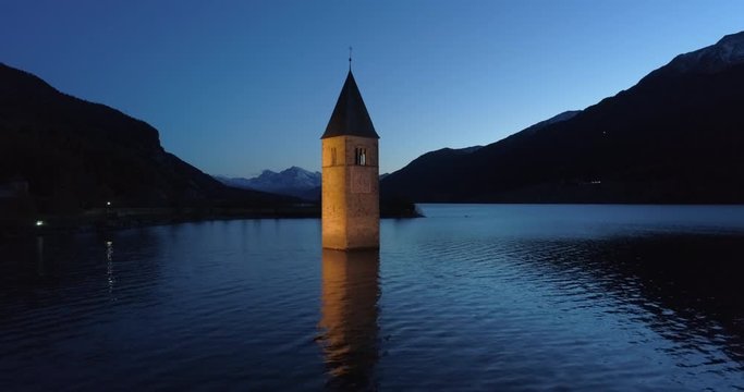 Aerial: The Lake Reschen Bell Tower at Night Before Dark Hills and Distant Mountains - South Tyrol, Italy