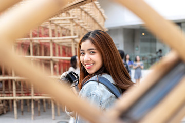 Portrait of young Asian woman tourist with digital camera in hands. Travel and vacation concept.